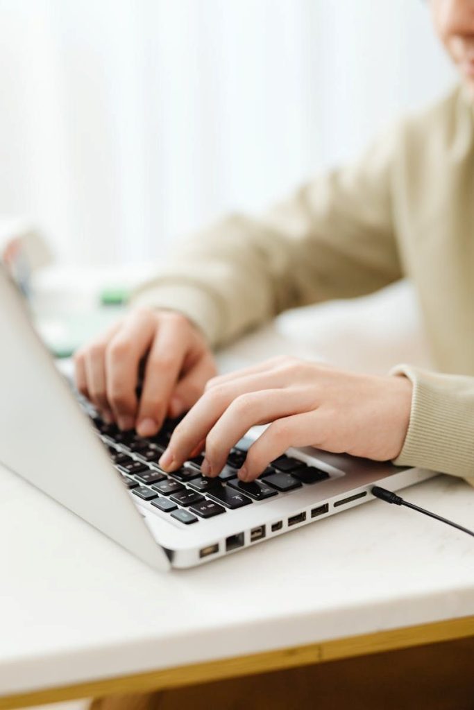Close-up of copywriter typing on a laptop, supporting remote work.
